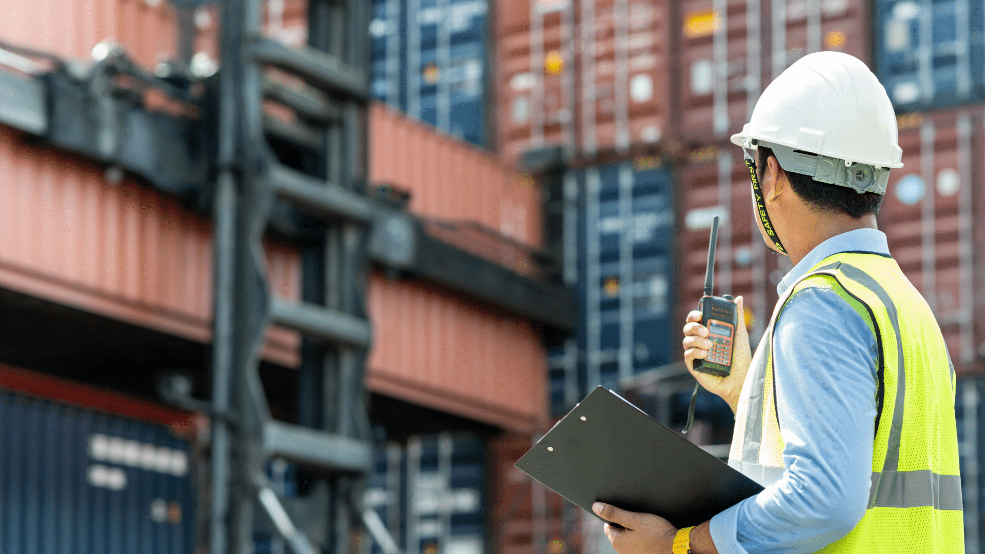 man holding a walkie talkie surrounded by shipping container