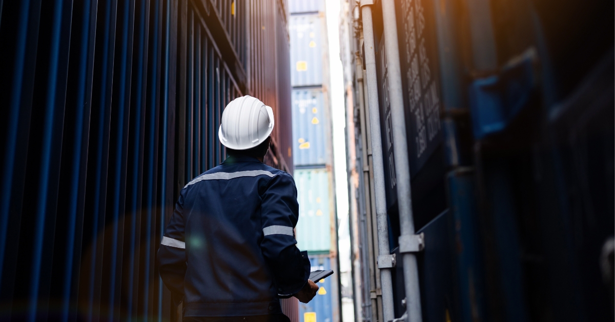 man looking up at shipping containers of freight