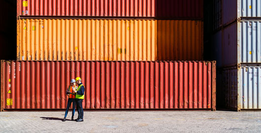 men talking in front of bright shipping containers