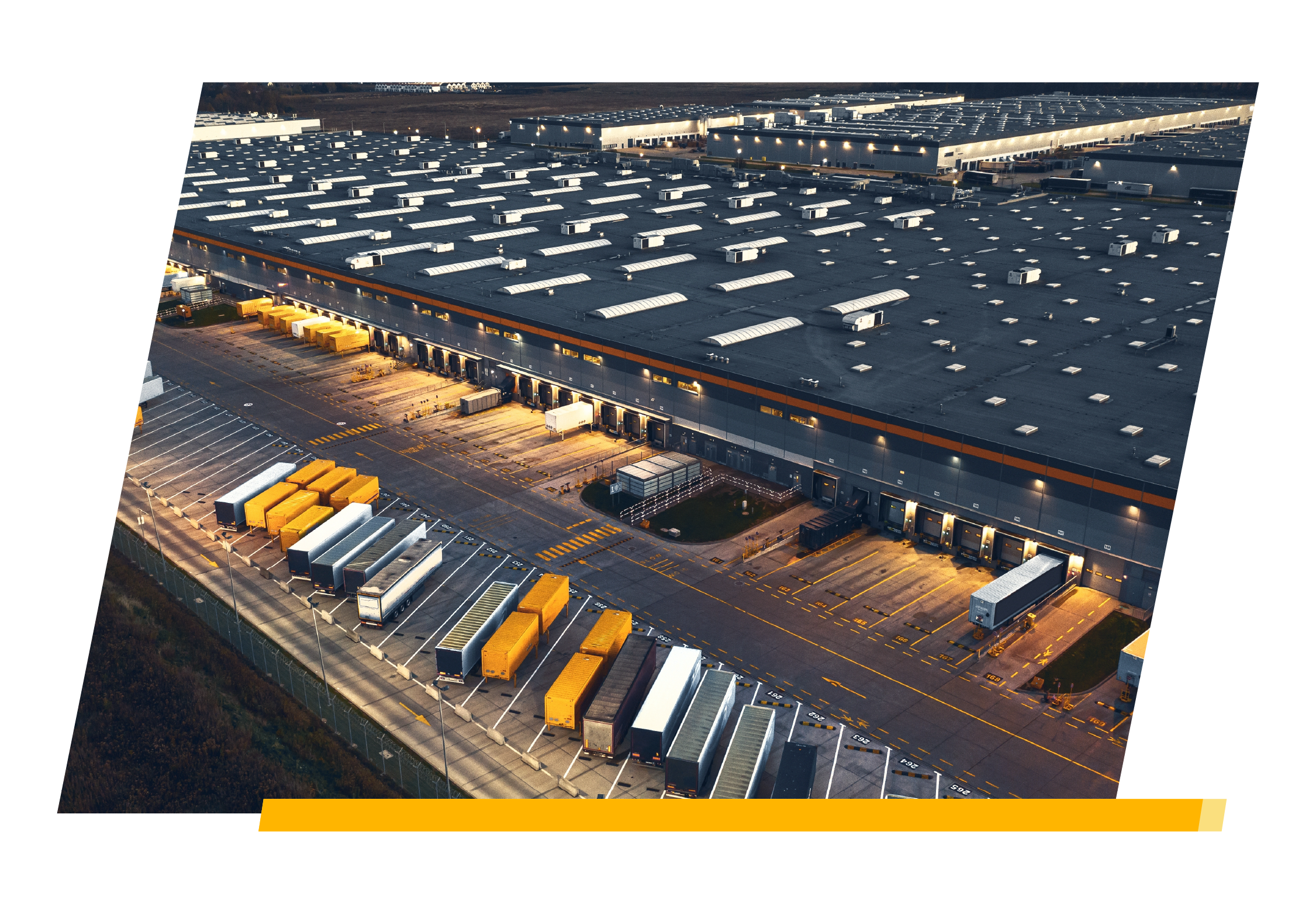 an aerial view of a warehouse with trailers backed up to the loading dock or parked in the parking lot