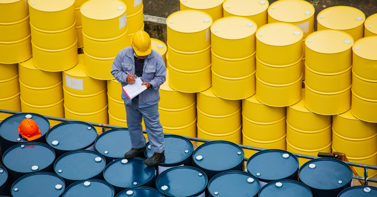 employee standing on top of oil barrels