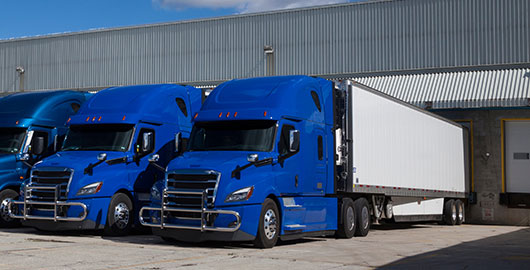 blue semi and white trailers parked at the loading dock