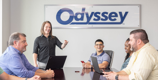 group of employees gathered around the conference room table at the Odyssey office