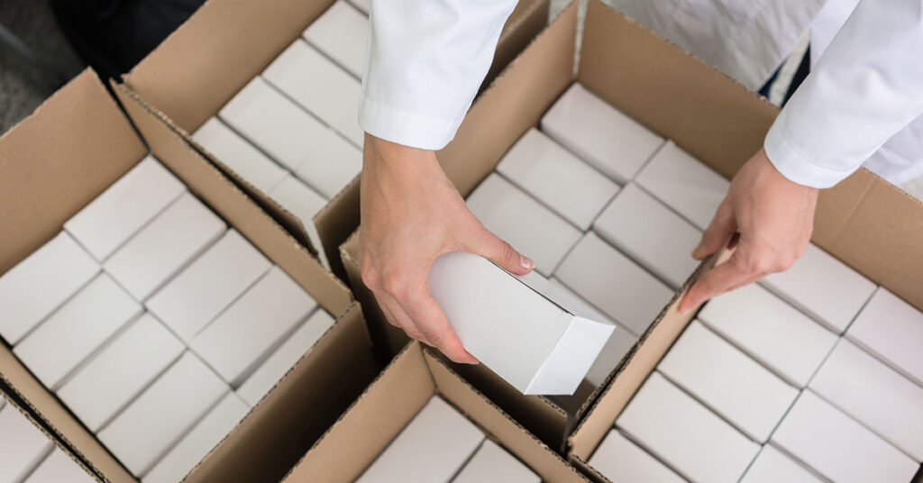 a person packing up kits into shipping boxes