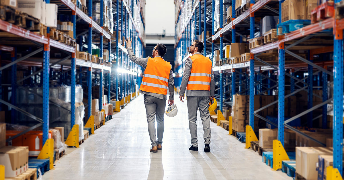 Two business men walking through a warehouse having a discussion