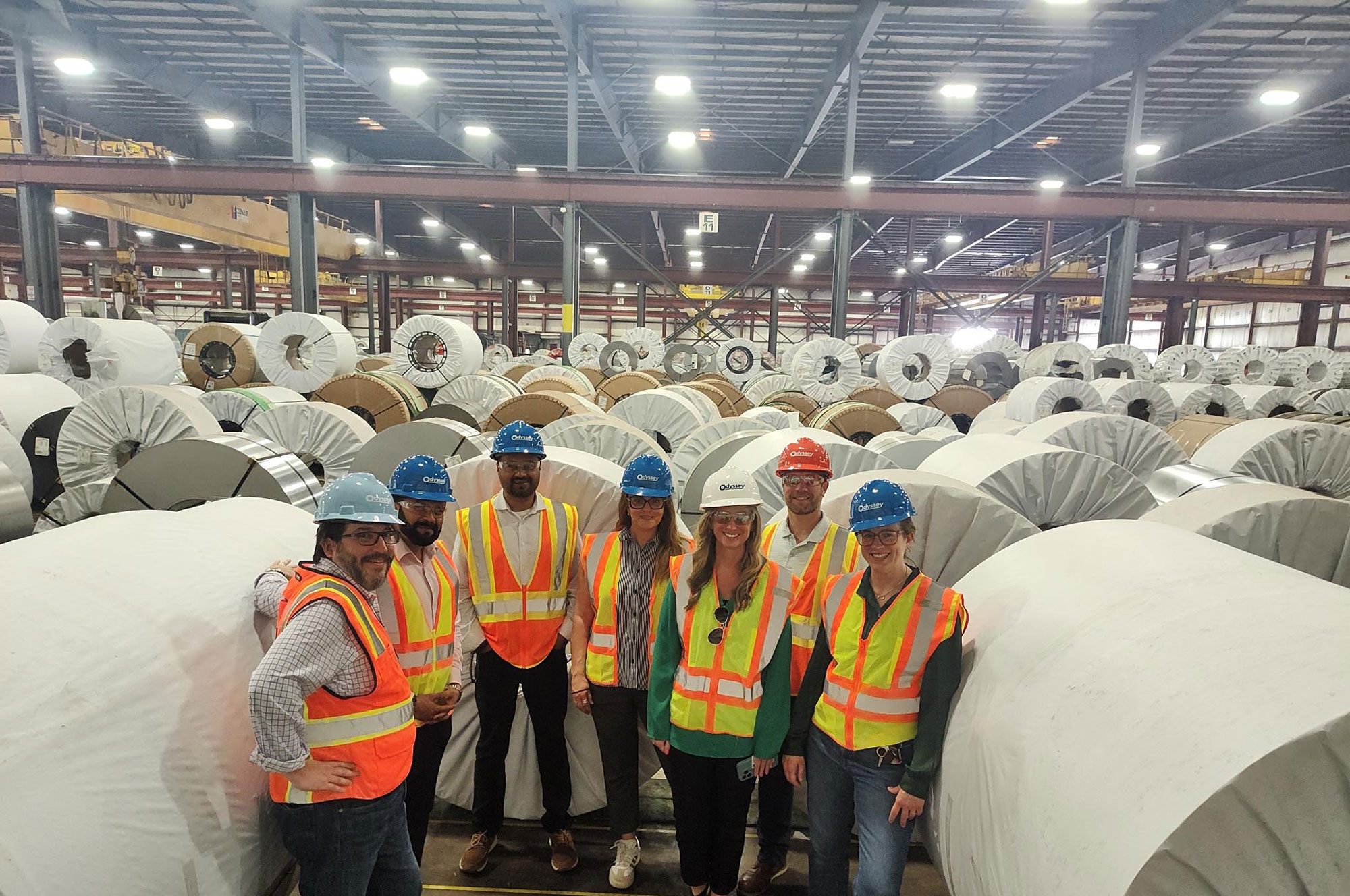 Odyssey team members standing next to metals in the warehouse