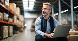 a man typing on a laptop in a warehouse